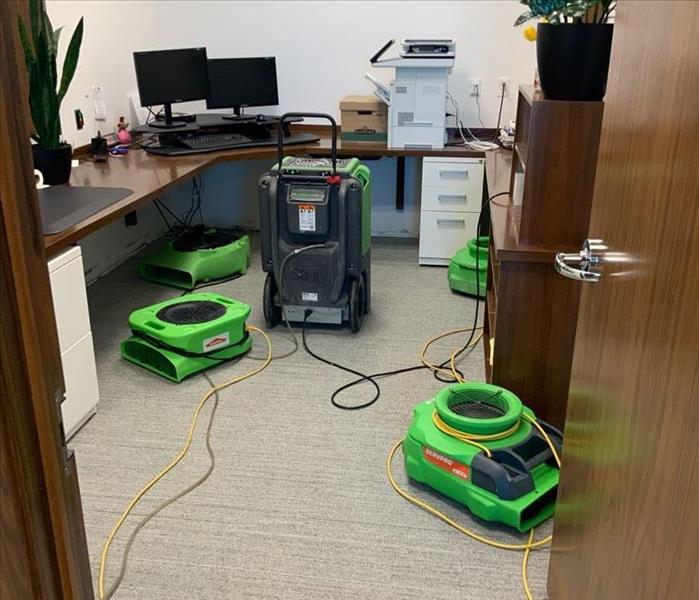 Four air movers on the floor of an office.
