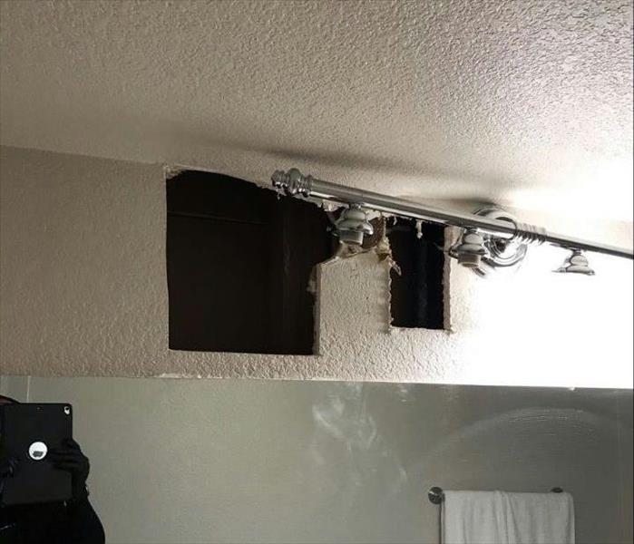 Hole cut in a wall above some lights. 