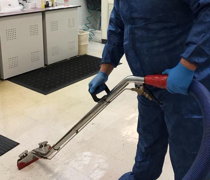 Employee in a blue protective suit cleaning.