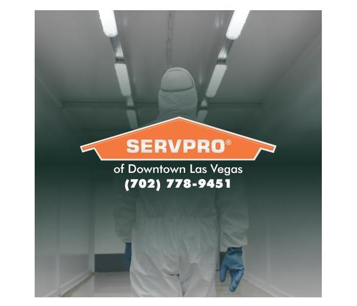 Person in PPE walking away with a SERVPRO logo over it.